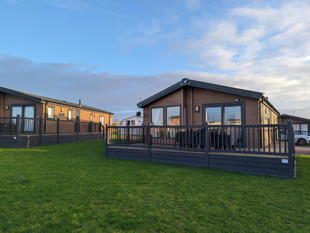 a row of modular homes on a lawn at Morrelo View 24, Cherry Tree Holiday park. in Great Yarmouth