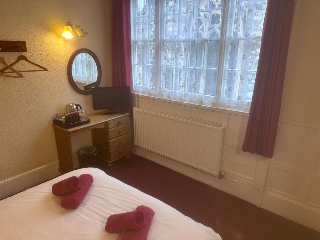 una camera da letto con pantofole rosse su un letto con finestra di Kings Arms Hotel a Sandwich