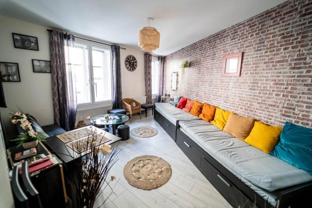 a living room with a couch against a brick wall at Double Appart Hypercentre Blois in Blois