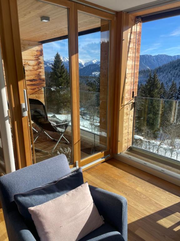 a room with a chair and a window with mountains at Pineview Waldhaus in Flims