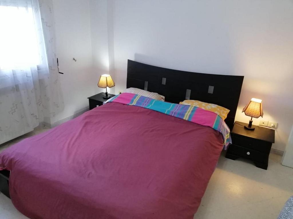 um quarto com uma grande cama roxa com 2 candeeiros em Holidays HOUSE em La Marsa