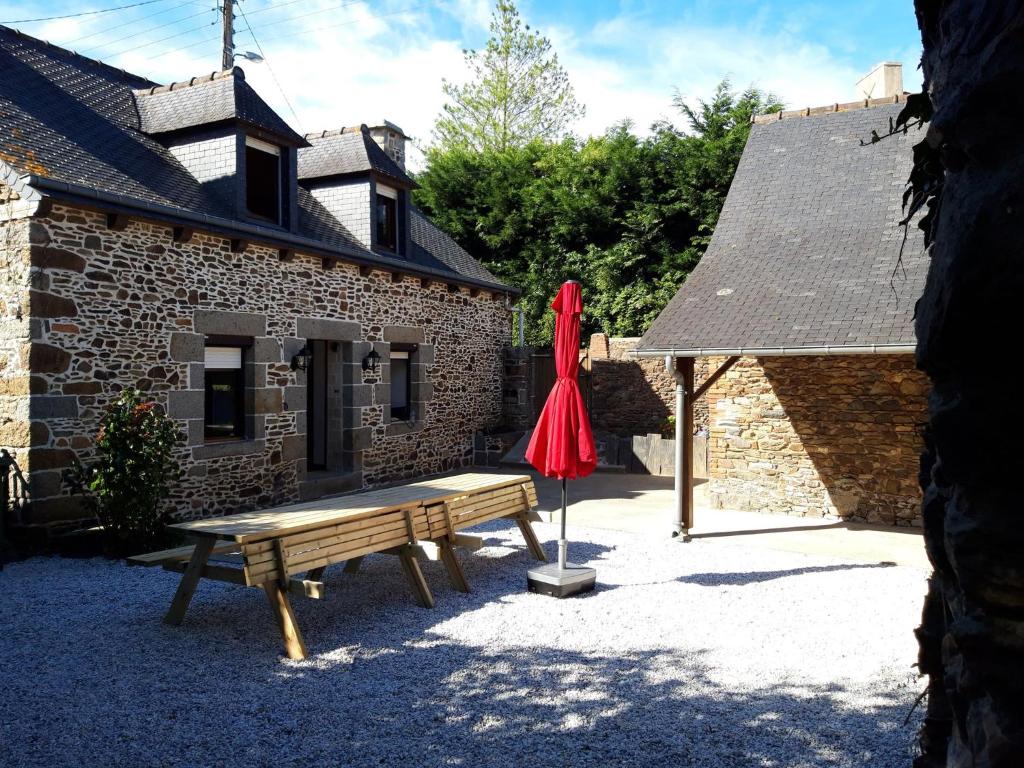 un banc en bois devant un bâtiment avec un parapluie rouge dans l'établissement Location Maison 4 / 8 personnes en Côtes D'Armor, à Étables