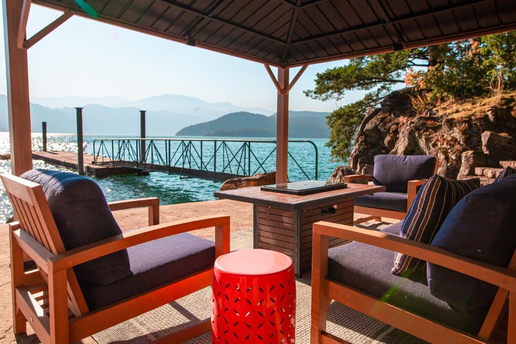 eine Terrasse mit Stühlen und einem Tisch mit Blick auf das Wasser in der Unterkunft The Overlook, Luxury Lakeside Home with Dock in Harrison Hot Springs