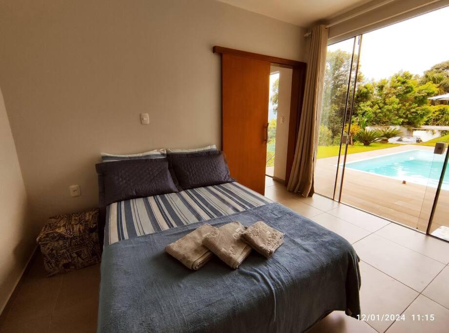 a bedroom with a bed with two pillows and a pool at Quiosque com piscina e vista in Encantado