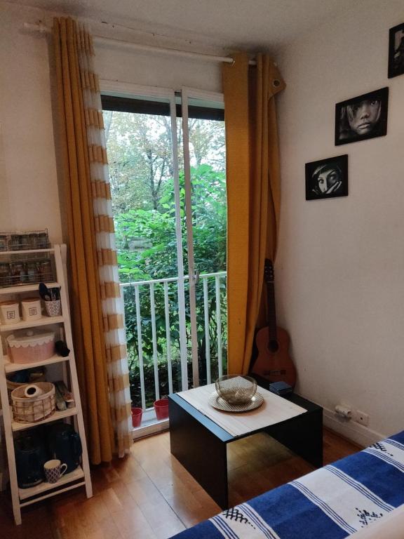 Habitación con cama y mesa frente a una ventana en Cozy Gateaway, en Neuilly-sur-Seine