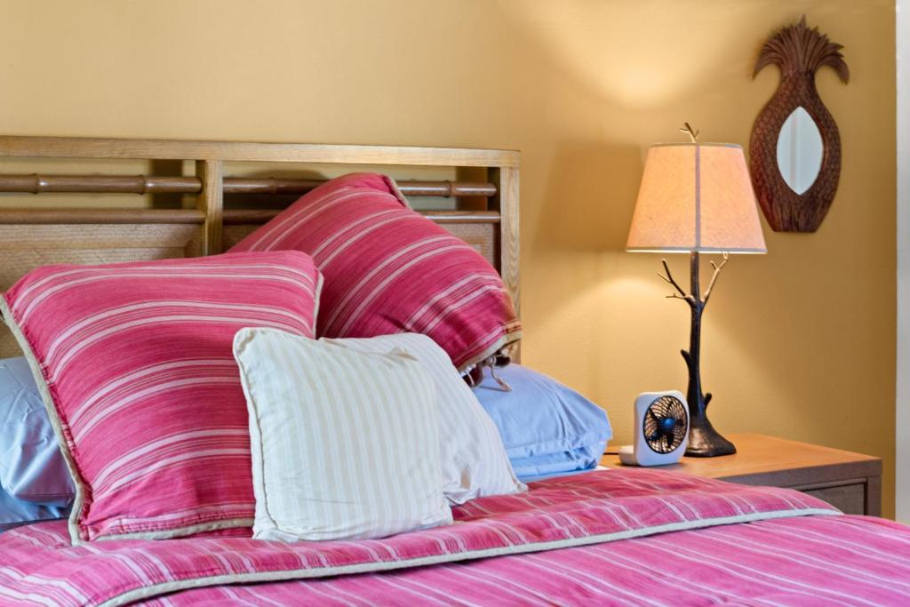 een slaapkamer met een bed met roze en witte kussens bij Studio with mini kitchen, pool and BBQ, Pre-Renovation Summer Sale in Kihei