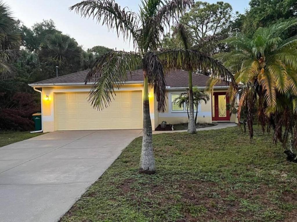 a house with two palm trees next to a driveway at Nice and Comfortable... in Rotunda-West