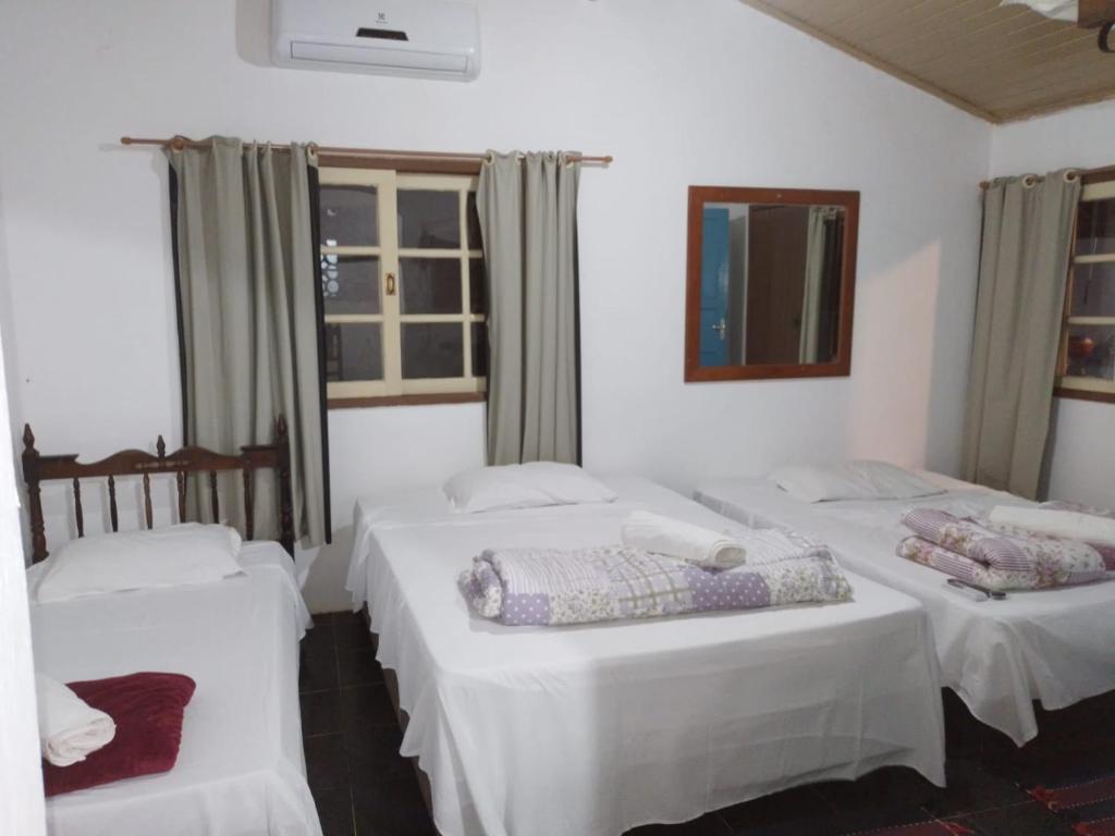 two beds in a room with white walls and windows at Casinha Centro histórico in Paraty