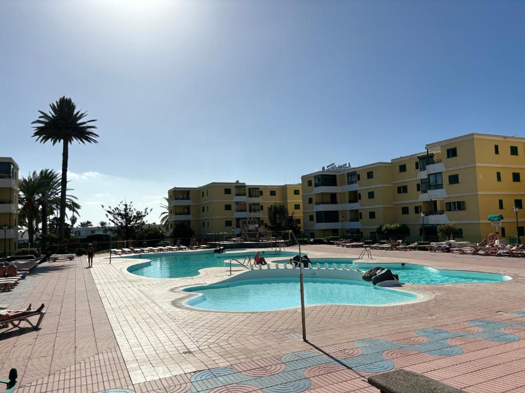 ein Pool in einem Resort mit Gebäuden im Hintergrund in der Unterkunft Las olas 214 in Maspalomas