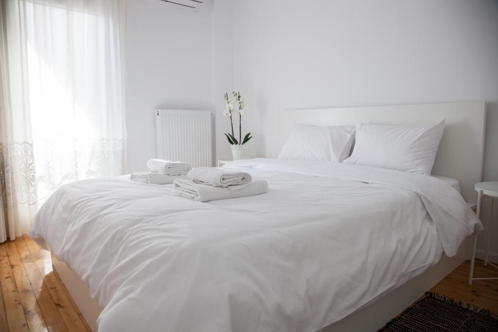 ein weißes Bett mit weißer Bettwäsche und Handtüchern darauf in der Unterkunft CASA Di TRE in Thessaloniki