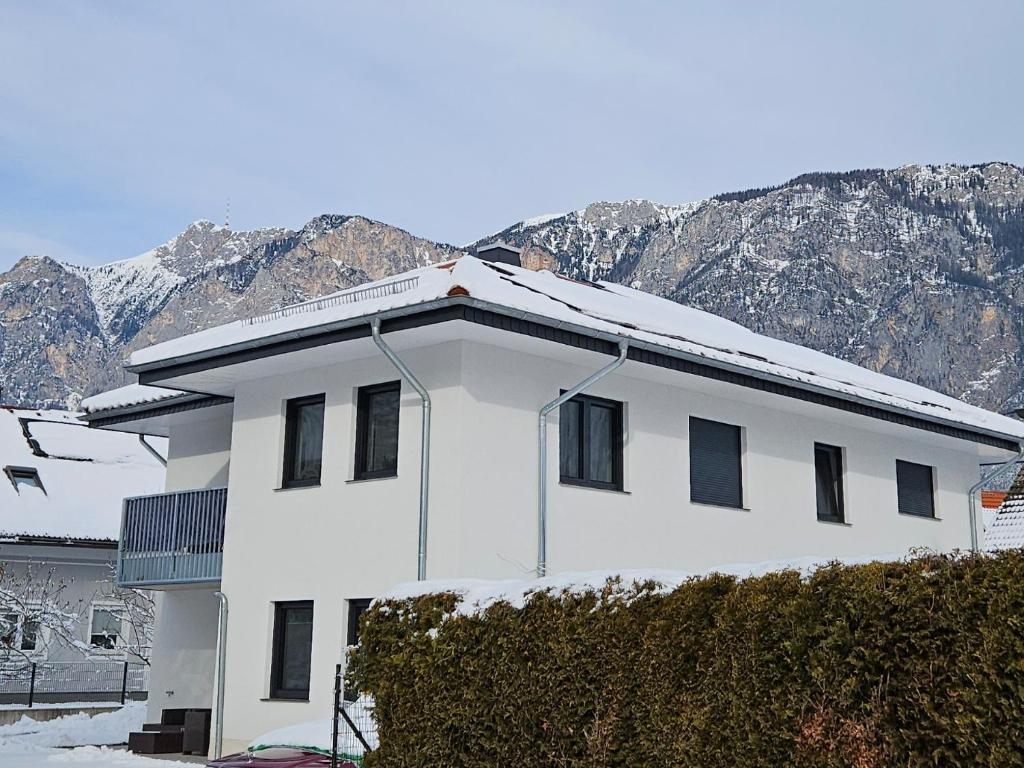 a white house with mountains in the background at Ferienwohnung in Arnoldstein in Arnoldstein