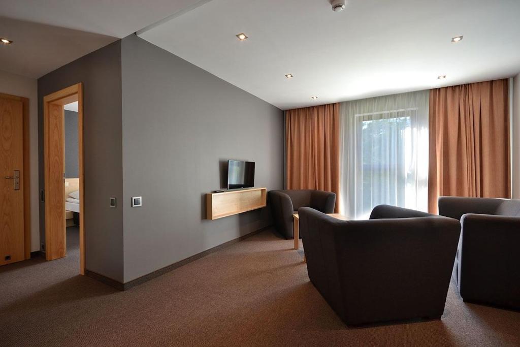 um quarto de hotel com cadeiras e uma televisão e uma cama em Rezydencja nad jeziorem Pestkownica em Pestkownica
