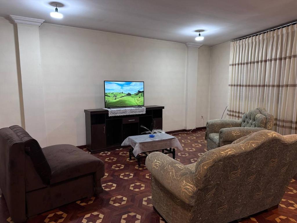 sala de estar con 2 sillas y TV de pantalla plana en Departamentos a su altura en La Paz en La Paz