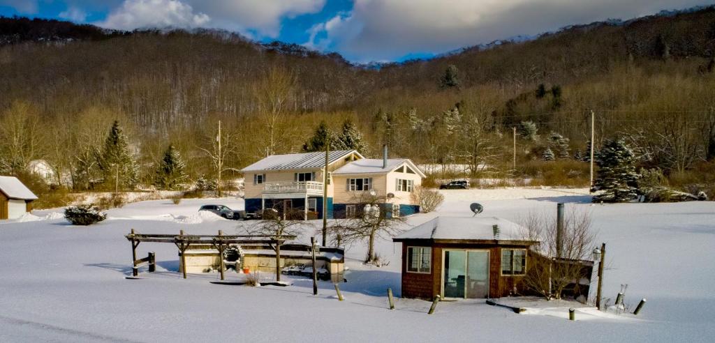 a house in the snow with snow covered ground at The Maples - Hot tub! Amazing views, pets welcomed in Ellicottville