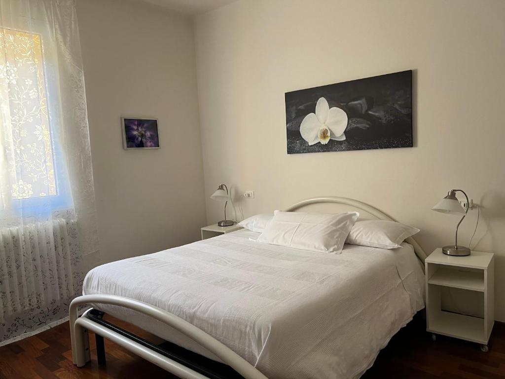 ボローニャにあるCasa Francia Alidosiのベッドルーム1室(白いベッド1台、ランプ2つ、窓付)