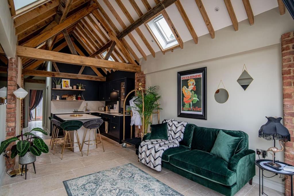 a living room with a green couch and a kitchen at Luxury private FARM BARN, Airport, NEC 