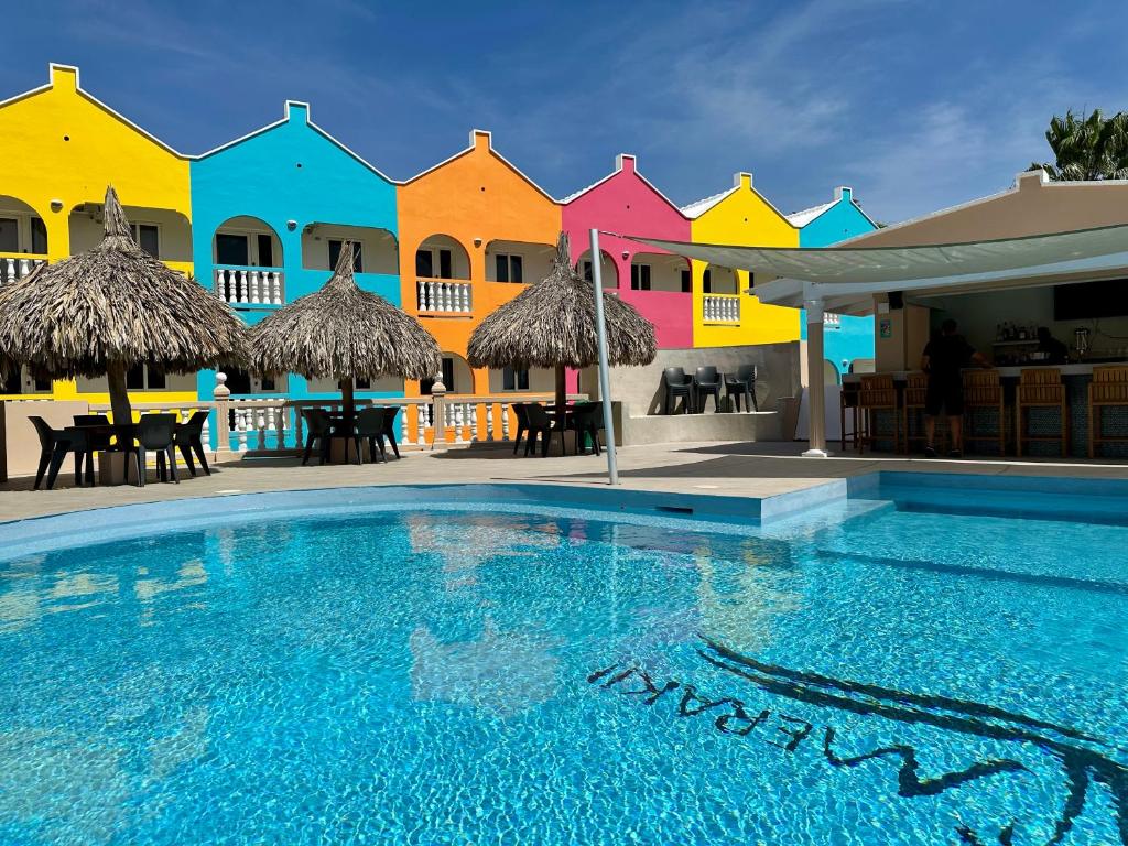 a pool in front of a row of colorful houses at MERAKII SEAVIEW ESCAPE CURACAO in Willemstad