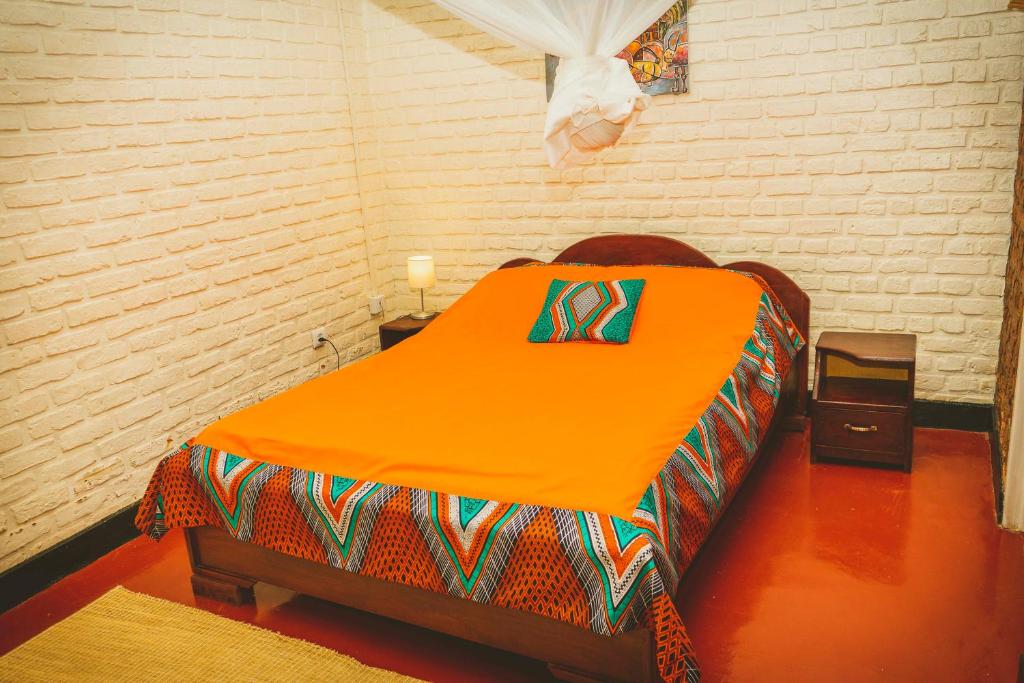 an orange bed in a room with a brick wall at Room in Guest room - Isange Paradise Resort in Ruhengeri