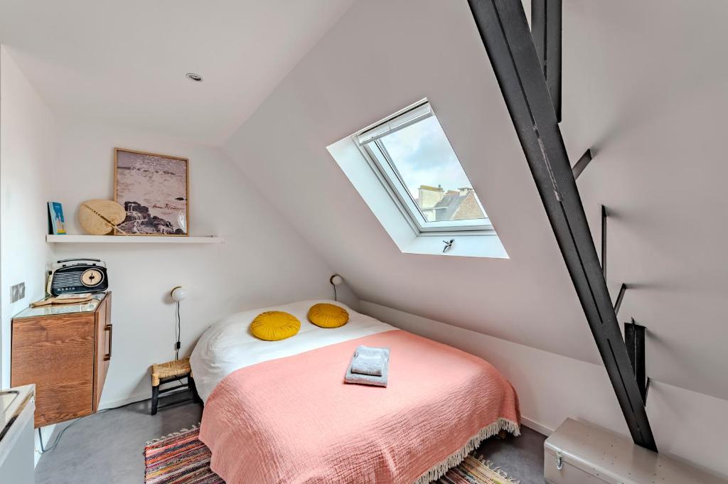 Schlafzimmer im Dachgeschoss mit einem Bett und einem Fenster in der Unterkunft Charmant studio à deux pas de la gare - Le Nichoir in Rennes