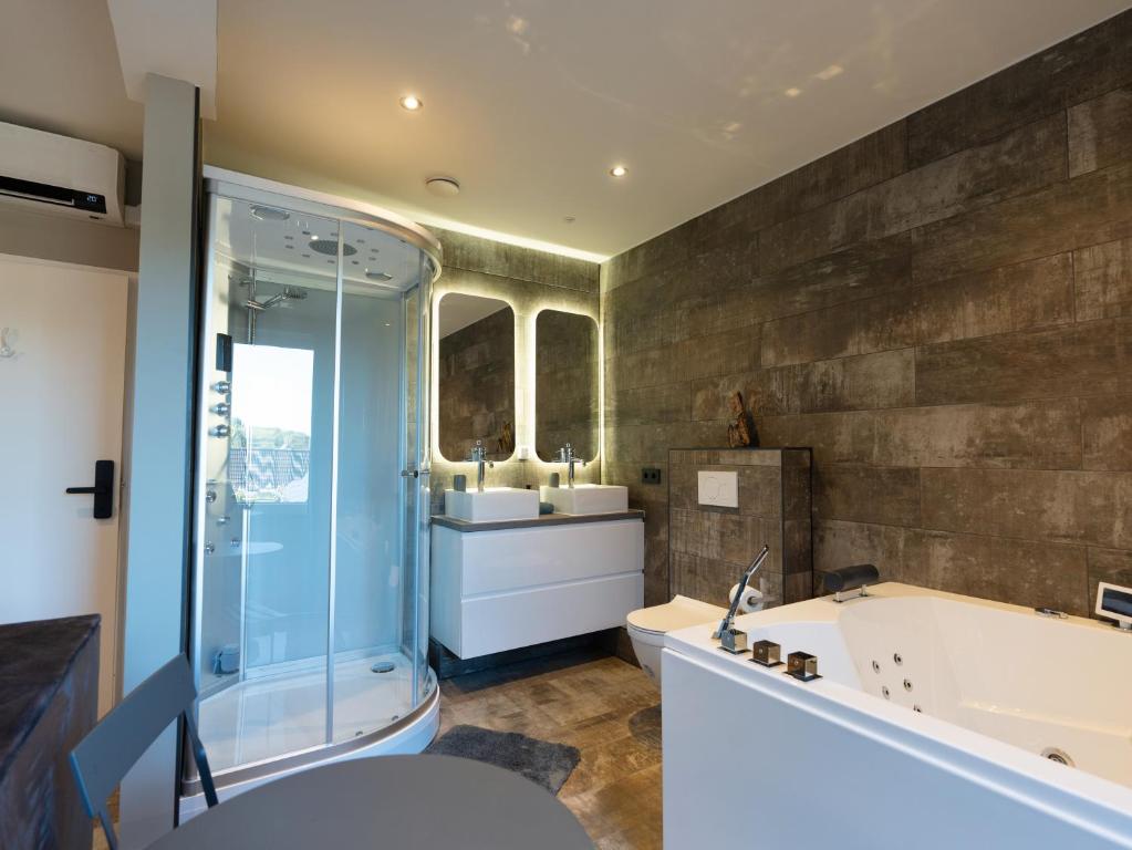 łazienka z 2 umywalkami, wanną i prysznicem w obiekcie Luxe kamer B&B Gezond aan Zee, met jacuzzi en stoomsauna, de wellnestuin buiten is te huur voor privé gebruik tegen meerprijs w mieście Ouddorp