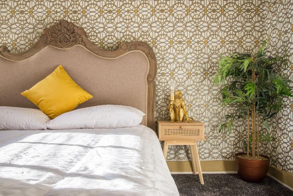 ein Schlafzimmer mit einem Bett mit gelbem Kissen und zwei Pflanzen in der Unterkunft Deluxe 4 Bed London House Nr Stratford in London