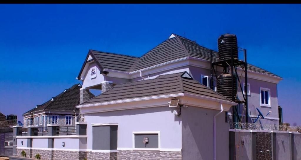 D'EXQUISITE APARTMENTS في إيبادان: منزل أبيض كبير على سقف أسود