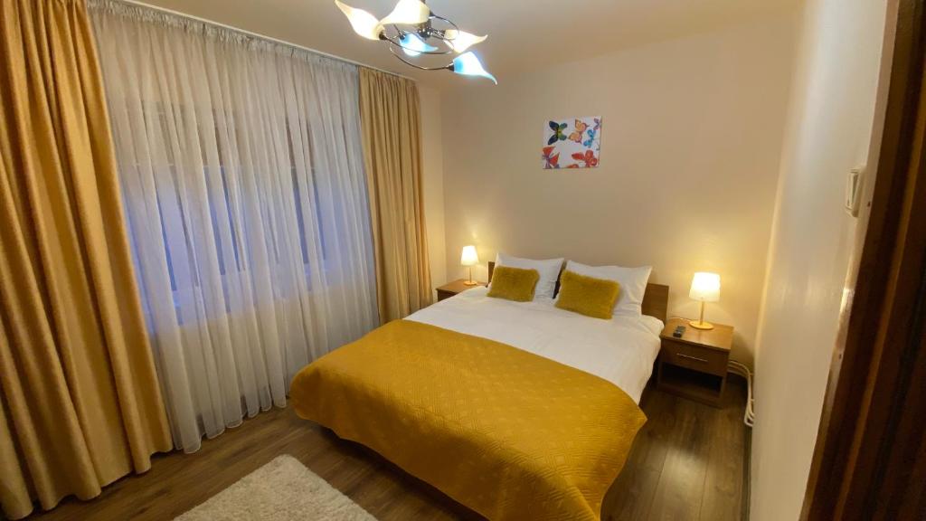 a bedroom with a bed with yellow sheets and a window at Apartament doua camere in Baia Mare