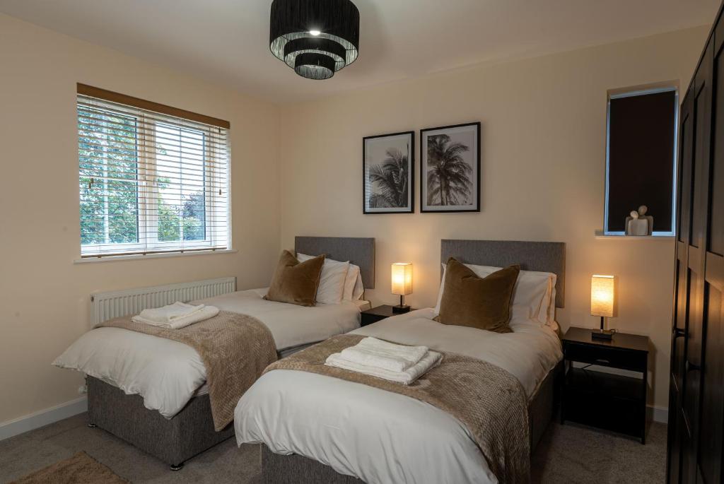 two beds in a bedroom with two lamps on tables at Elms House, sleeps 5, free parking in Reading