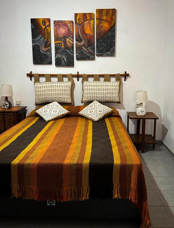 una camera da letto con un letto con tre dipinti sul muro di El Ocaso Villa Giardino a Villa Giardino
