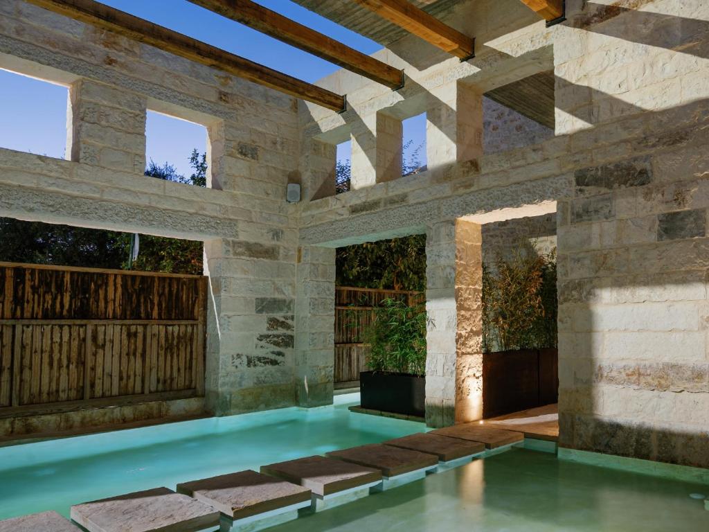 a swimming pool in a building with a stone wall at Amalen Suites Adults Only in Rethymno