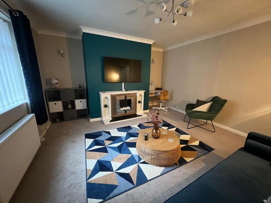 uma sala de estar com um sofá, uma mesa e uma lareira em Stylish & Centrally Located em Chester-le-Street