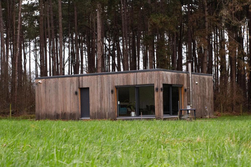 un pequeño edificio de madera en un campo de césped en Vakantiewoning 't Bruggeneindje, en Heist-op-den-Berg