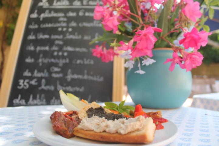 a sandwich on a plate on a table with flowers at Auberge des Glycines in Porquerolles