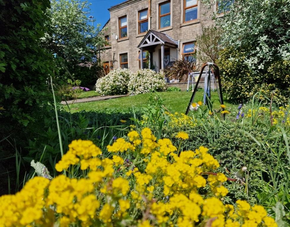 un jardín con flores amarillas frente a un edificio en the lodge@ beechwood house, en Mossley