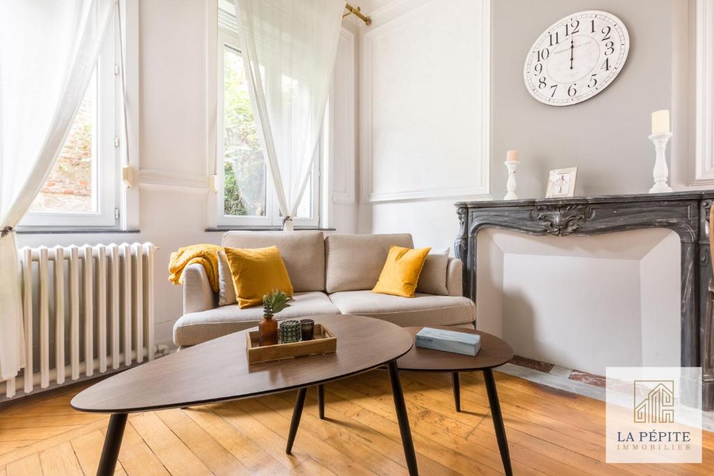 a living room with a couch and a clock on the wall at Residence Belle Etoile in Valenciennes