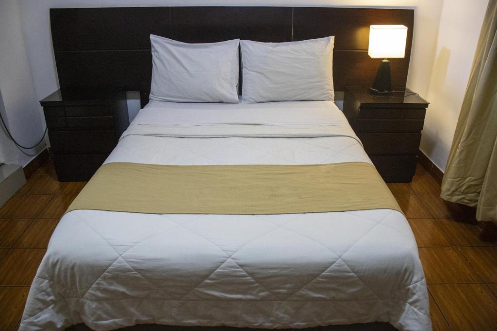 Cama en habitación de hotel con colcha blanca en Plaza Mayor Lima, en Lima