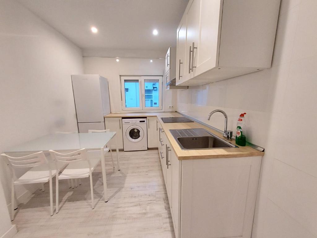 a kitchen with white cabinets and a table and a sink at Céntrico apartamento in Santa Cruz de Tenerife