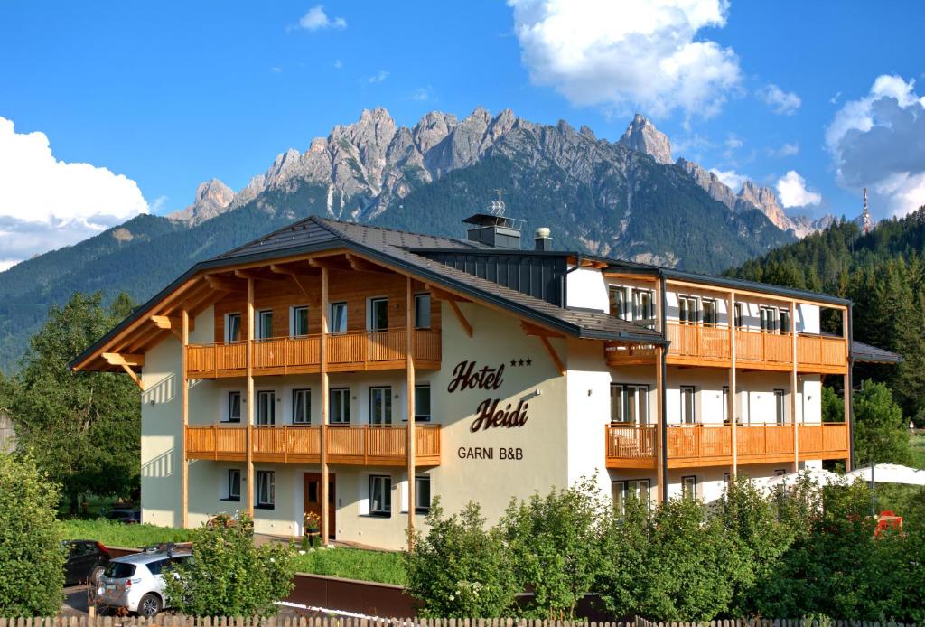 un grand bâtiment avec des montagnes en arrière-plan dans l'établissement B&B Hotel Heidi, à Dobbiaco