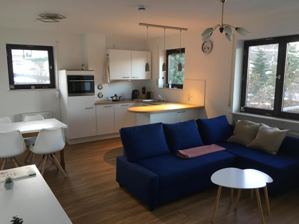 a living room with a blue couch and a kitchen at Apartment Henri in Schönwald