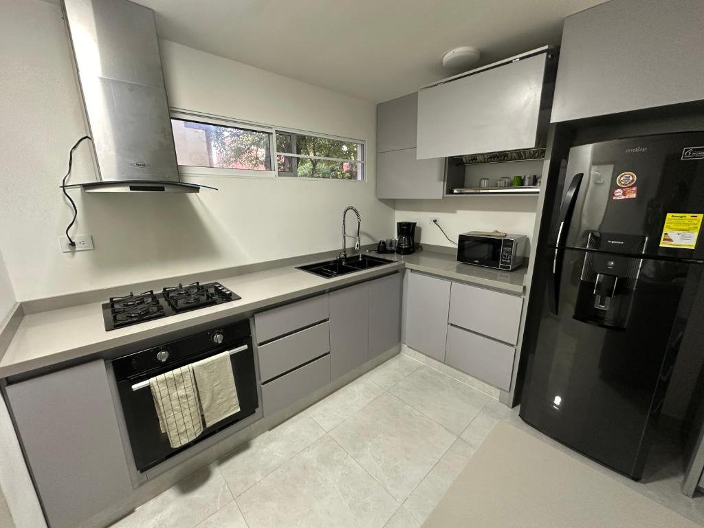 卡利的住宿－Unidad cerca a cosmocentro，厨房配有白色橱柜和黑色冰箱。