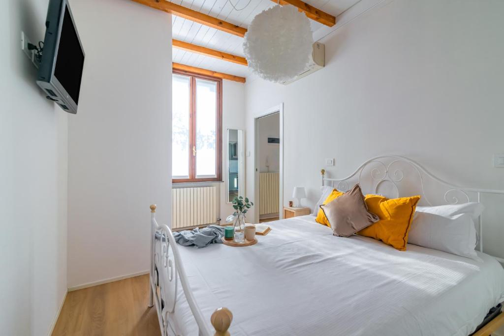 una camera da letto con un letto bianco e cuscini arancioni di La Corte 48 - Pavia City - by Host4U a Pavia