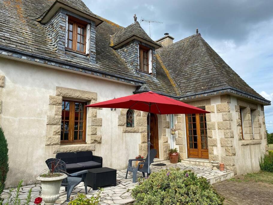 een huis met een patio met een rode parasol bij Grande maison de campagne in Lantic