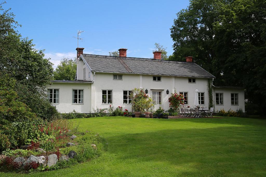 ein weißes Haus mit einem großen Garten mit Rasen sidx sidx sidx in der Unterkunft Olsbacka Gård in Falun