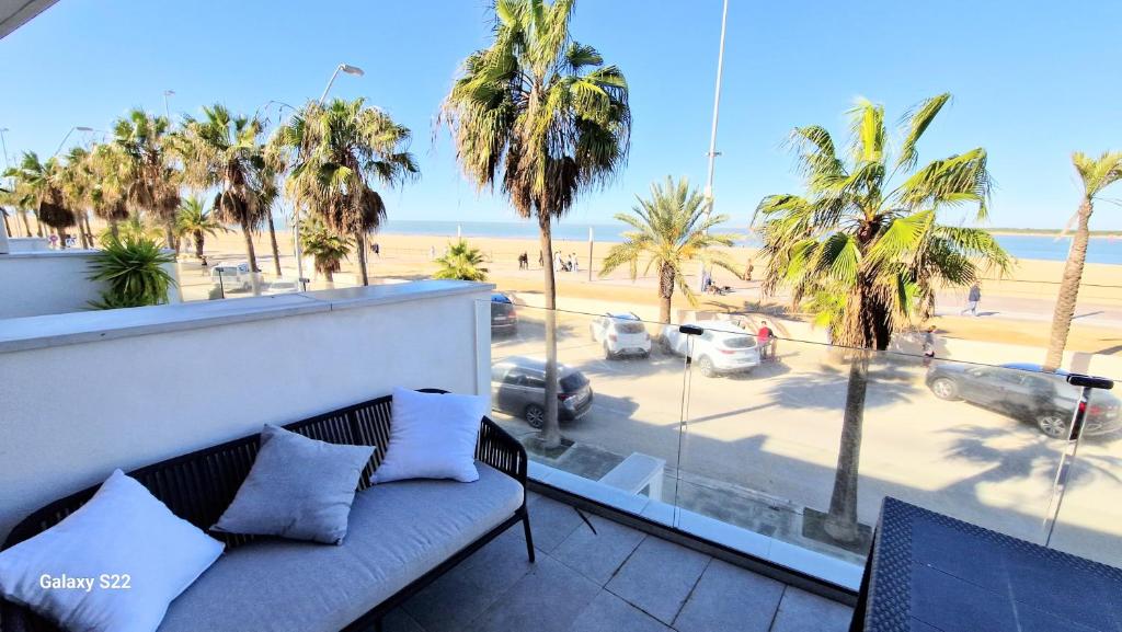 a couch on a balcony with a view of a beach at Boutelou playa con vistas al mar in Sanlúcar de Barrameda