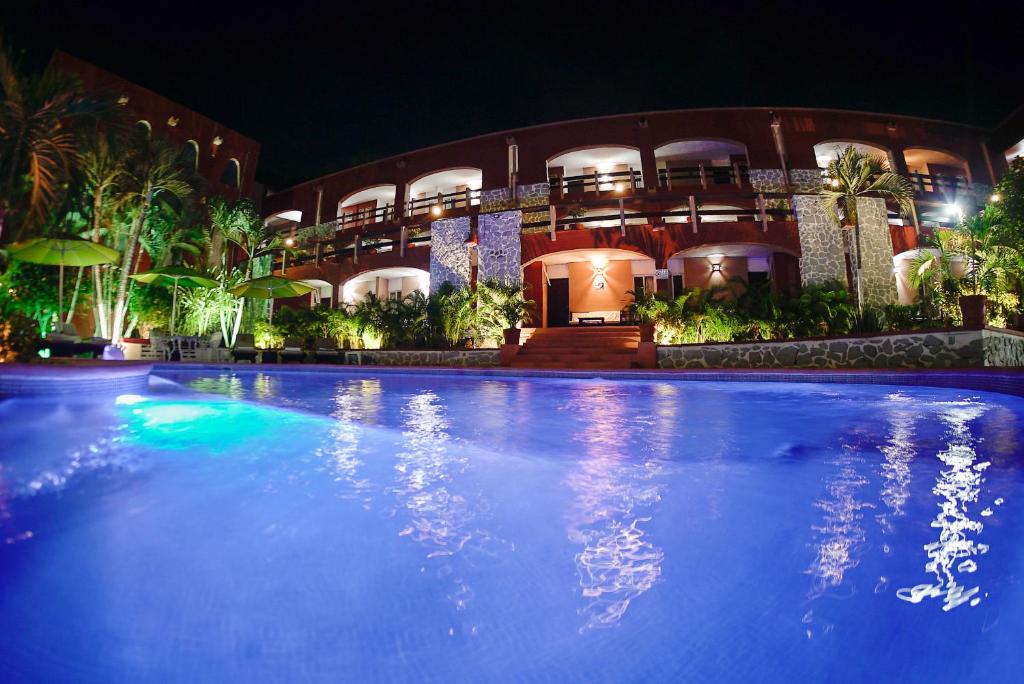 a large swimming pool in front of a building at night at Hotel Zihua Caracol in Zihuatanejo