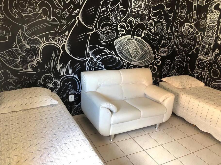 um quarto com uma cadeira e uma parede com graffiti em Casa em frente a praia em Vila Velha