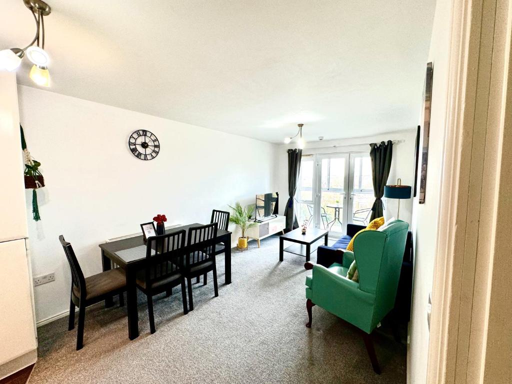 a living room with a table and a green chair at Bright & Spacious Flat - Perfect for Exploring London , Slough & Windsor! in Slough