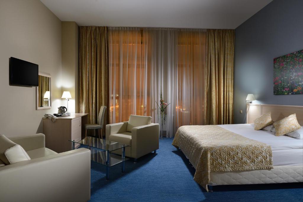 um quarto de hotel com uma cama e uma cadeira em Triumph Hotel em Obninsk