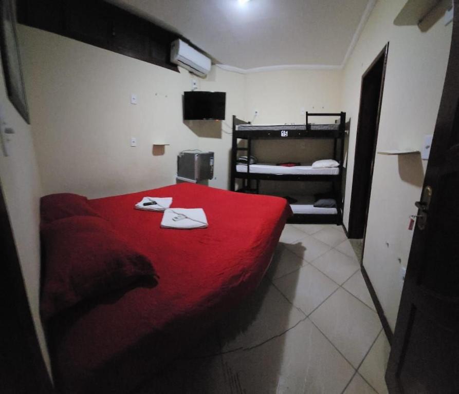 um pequeno quarto com uma cama vermelha com toalhas em Prédio Atalaia - Praia Grande Arraial do Cabo em Arraial do Cabo