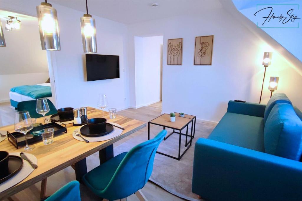 - un salon avec un canapé bleu et une table dans l'établissement Homely Stay - Urban Oasis Apartments, à Moosburg an der Isar